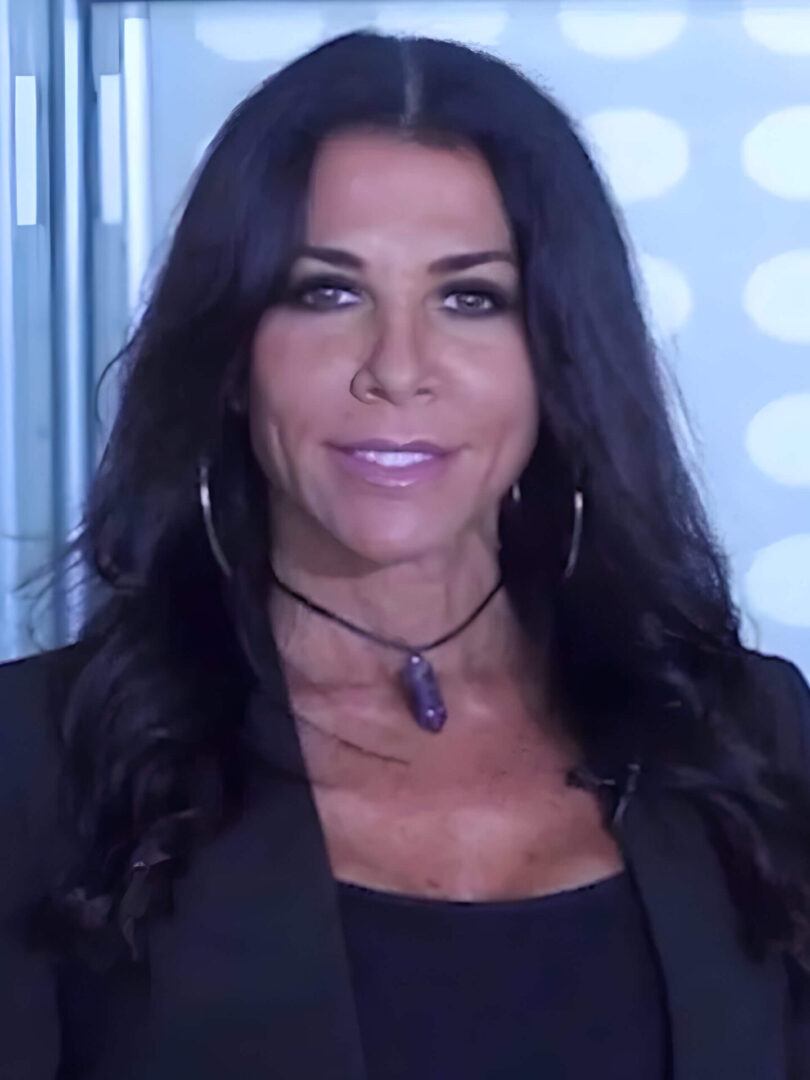 A woman with long black hair wearing a necklace.