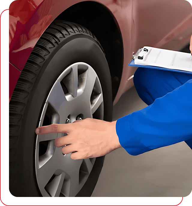 A person is pointing to the tire of a car.