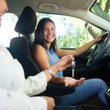 Teen driver behind the wheel with parent passenger, representing first-time driver education and car safety.